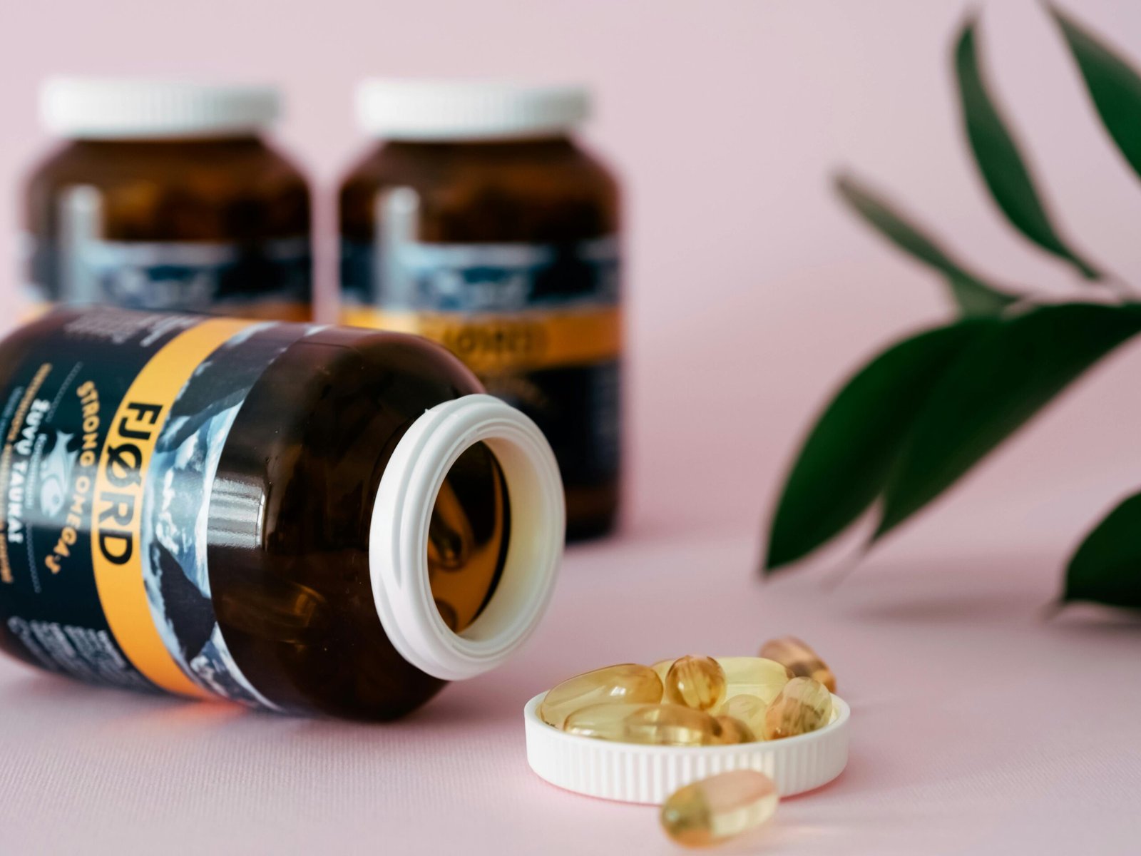 Close-up of omega-3 capsules and bottles on a pink background, ideal for health and wellness themes.